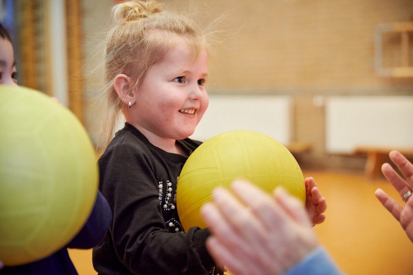 peuter speelt met de bal in de gymzaal.